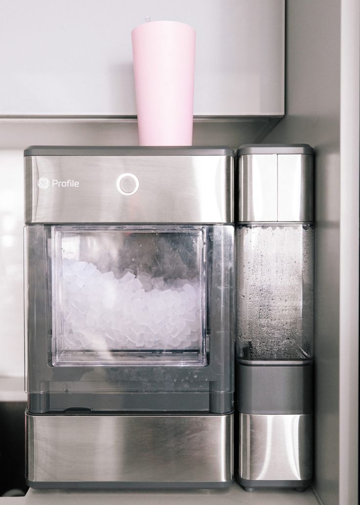 a stainless steel microwave oven with ice in the door and a pink cup on top