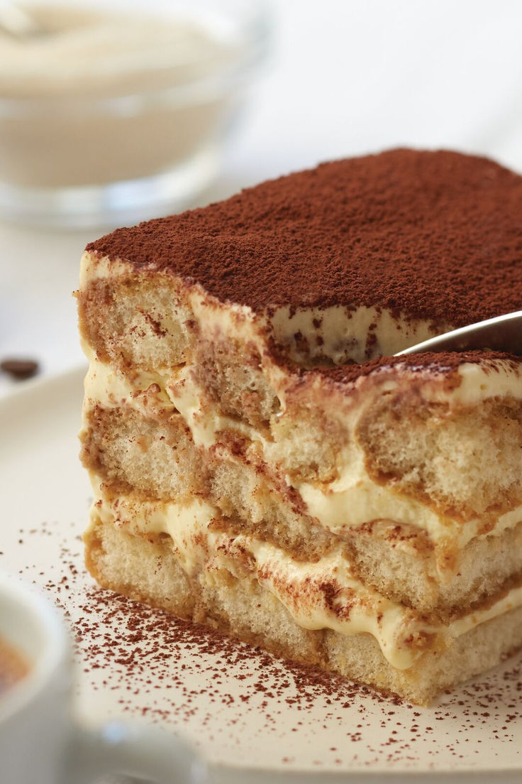 a piece of cake on a plate with a spoon in it and some coffee beans