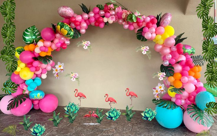 an arch made out of balloons with flamingos and flowers