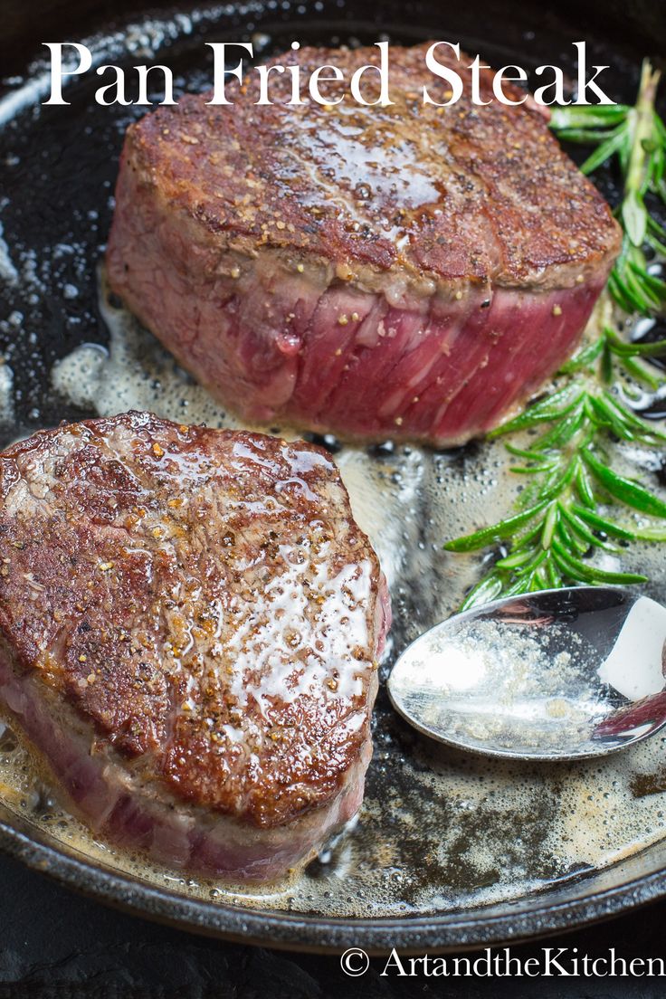 two steaks sitting on top of a pan covered in seasoning next to a spoon