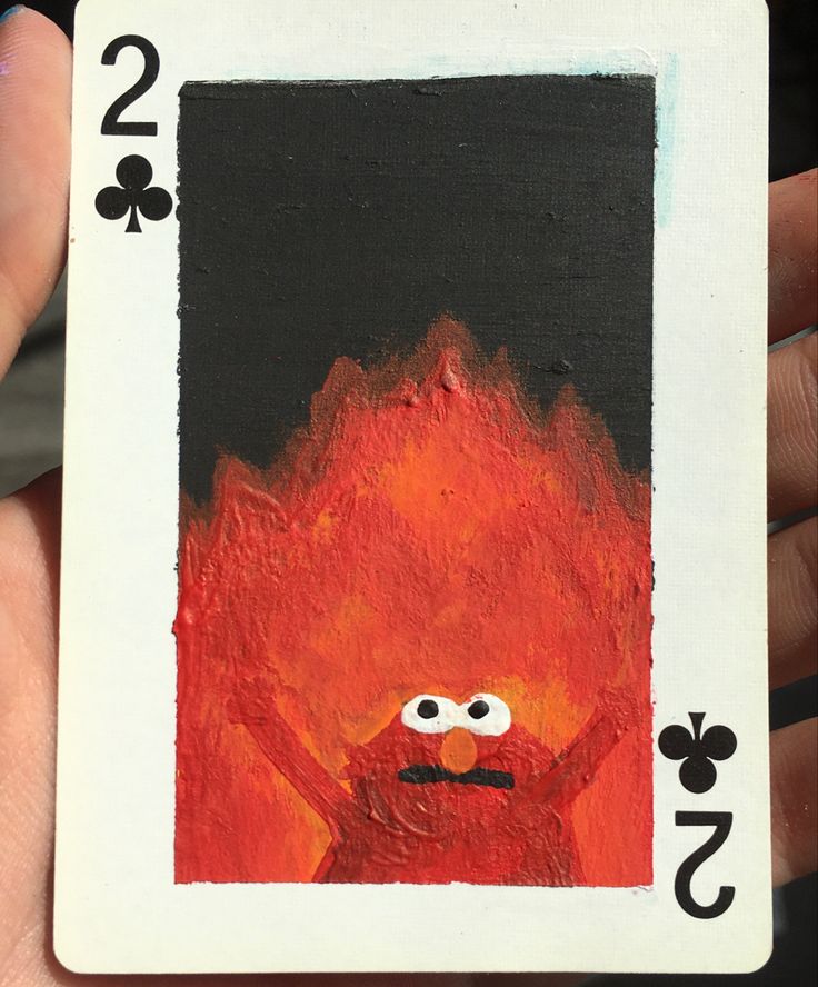 a hand holding up a playing card with an image of a fire monster on it