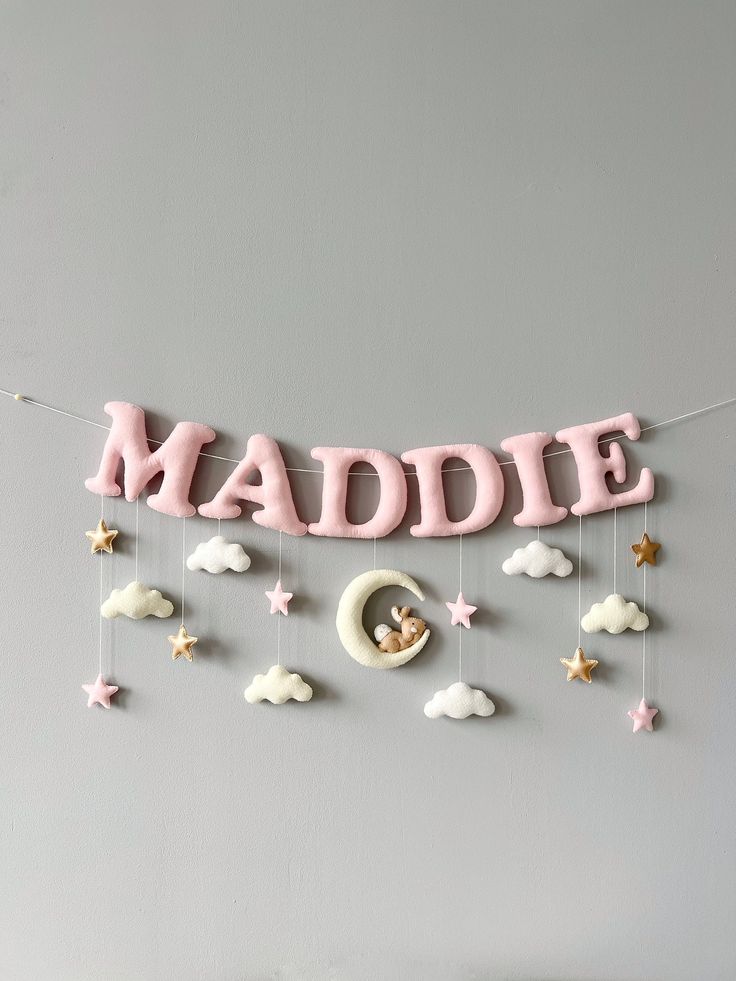 a baby's name sign hanging on the wall with clouds and stars around it