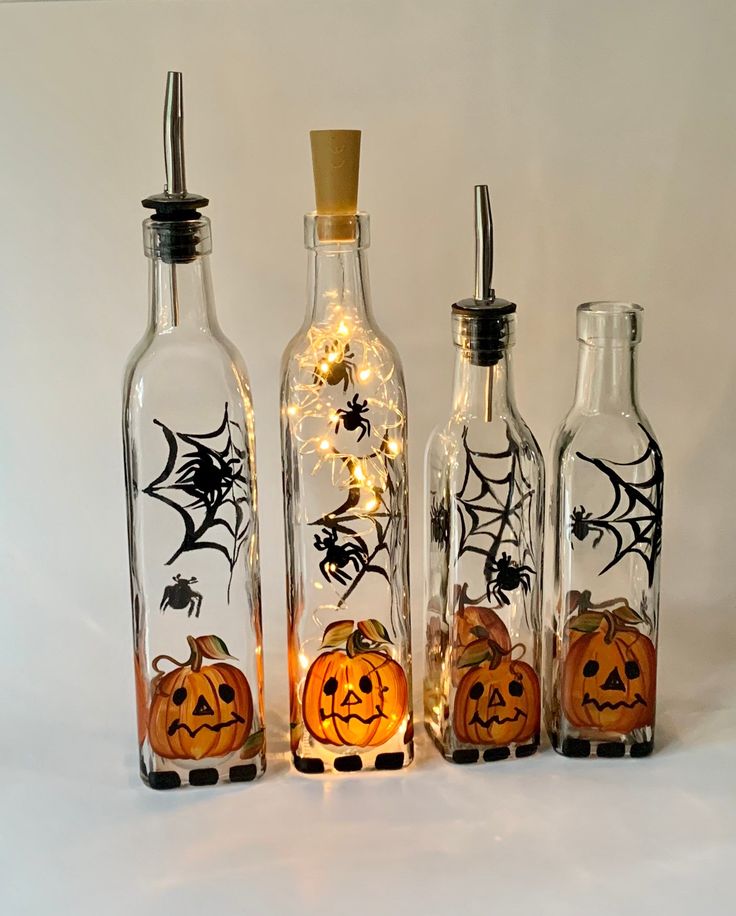 three bottles with pumpkins and spider web on them