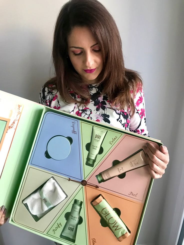 a woman holding an open box with different types of skin care products in it's sides