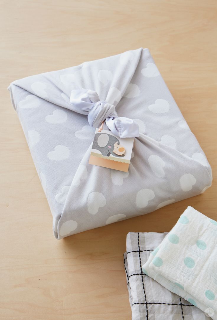 a wrapped present sitting on top of a wooden table next to two folded napkins