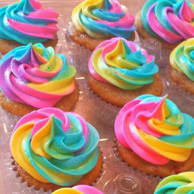 colorful cupcakes with icing being frosted and then decorated to look like rainbow