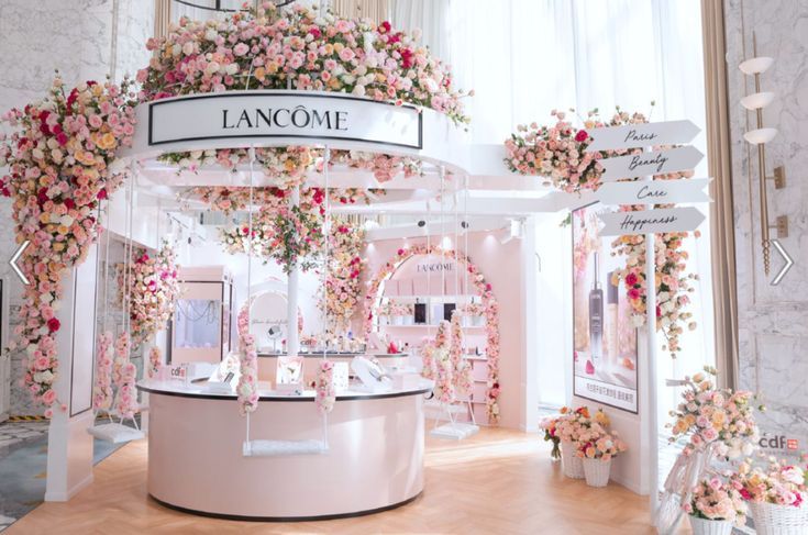 a flower shop with pink and white flowers on the walls, chandeliers and signage