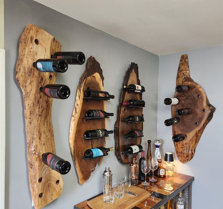 several wine bottles are lined up on the wall next to two wooden racks holding wine glasses