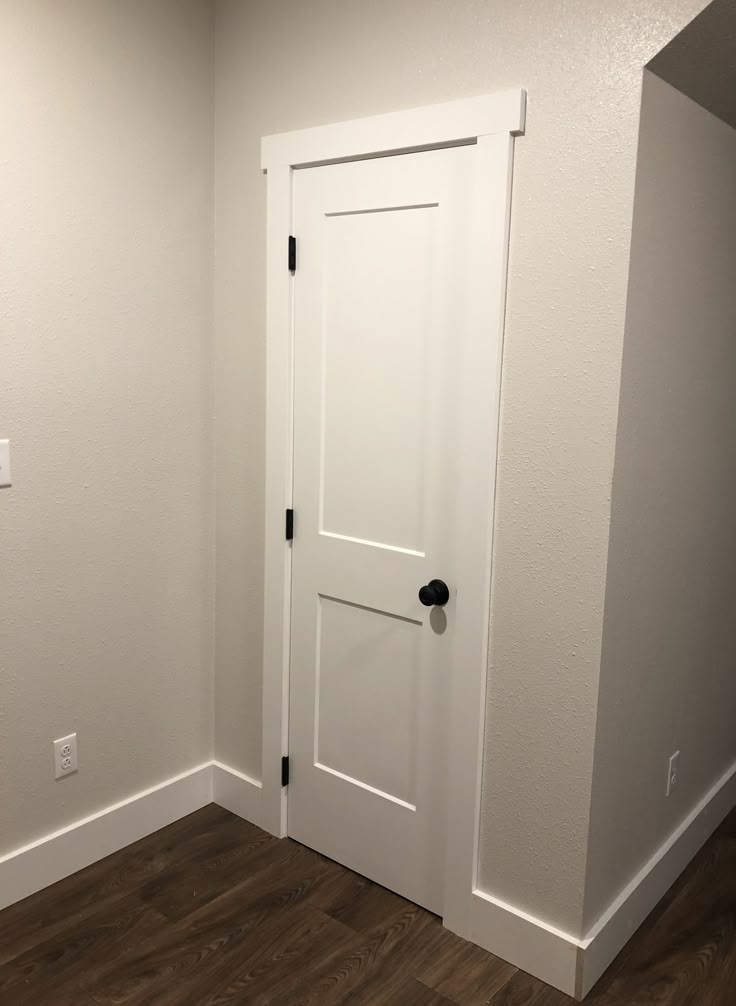 an empty room with a white door and wood floor