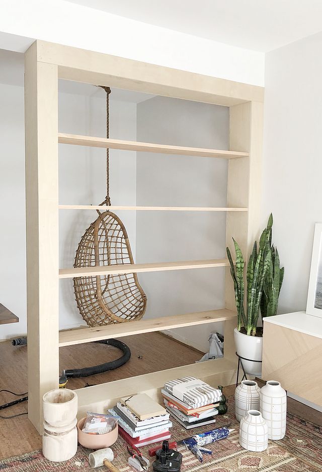 a living room with bookshelves and plants on the floor in front of it