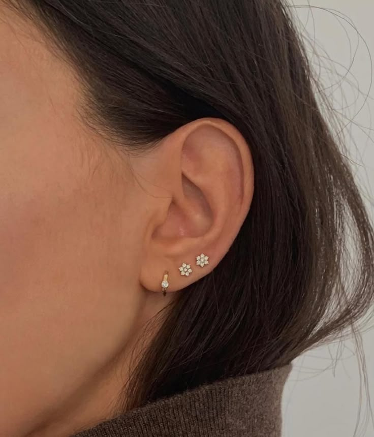 a woman wearing an earring with three small flowers on it