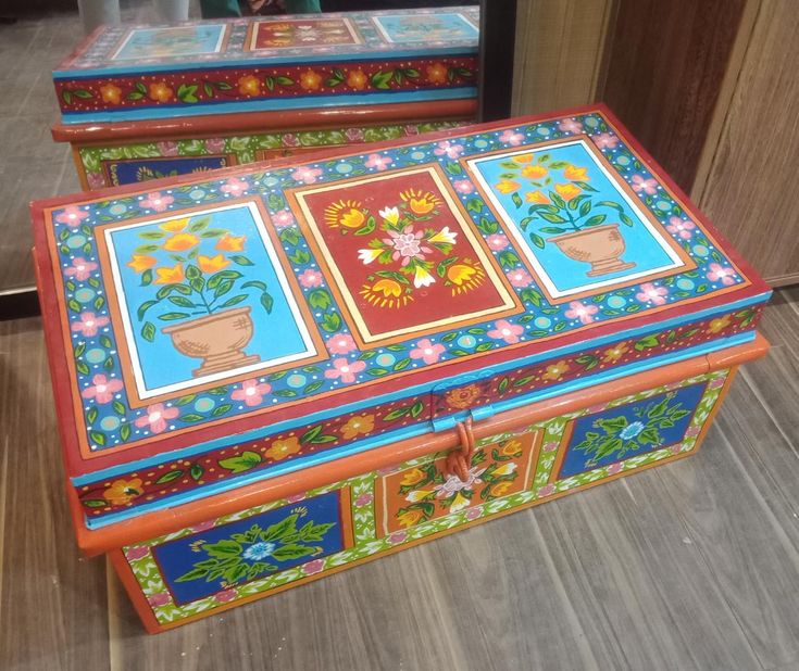 two colorful painted boxes sitting on top of a wooden floor