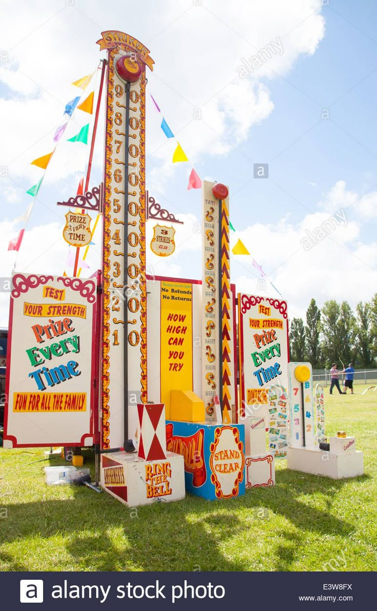 an amusement park ride with signs and flags on the grass, in front of a blue sky