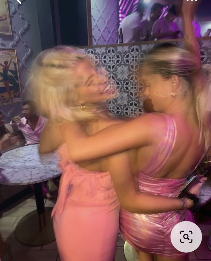 two women in pink dresses dancing at a party