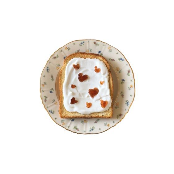 a piece of bread with white frosting and hearts on it sitting on a plate