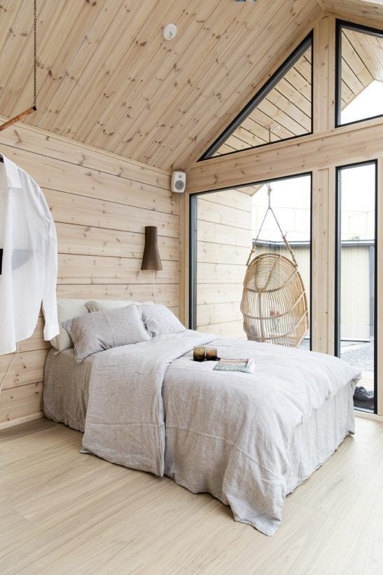 a bed in a bedroom with wooden walls and flooring next to an open window