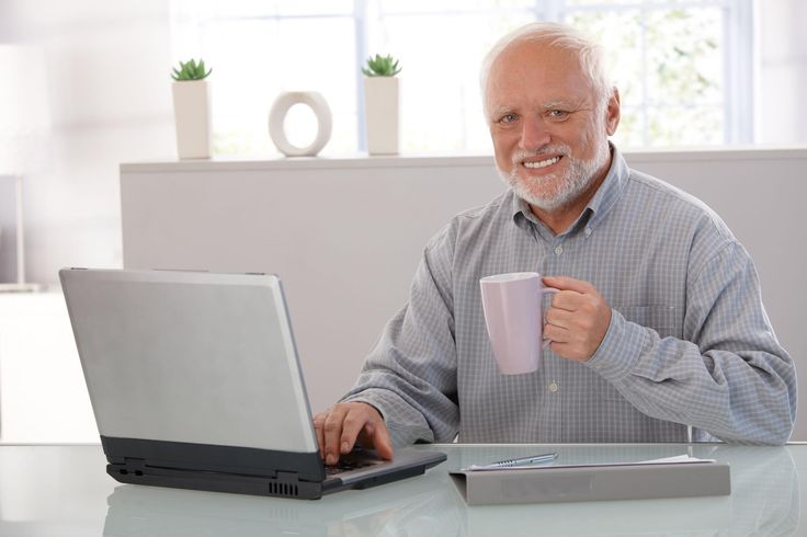 a man sitting at a table with a laptop and coffee cup in front of him