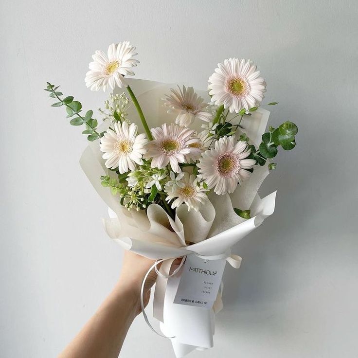 a hand holding a bouquet of white flowers