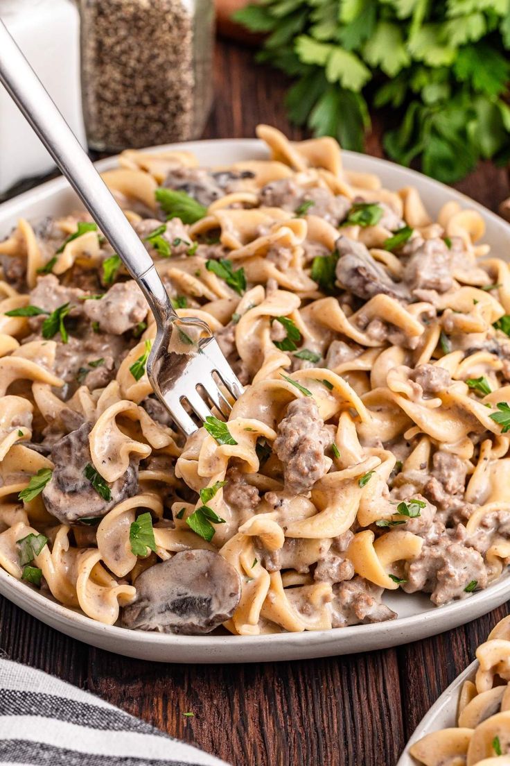 a plate full of pasta with meat and parsley on the side, ready to be eaten