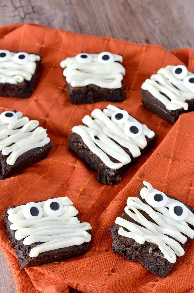 halloween brownies with white icing and eyes on an orange cloth covered tablecloth