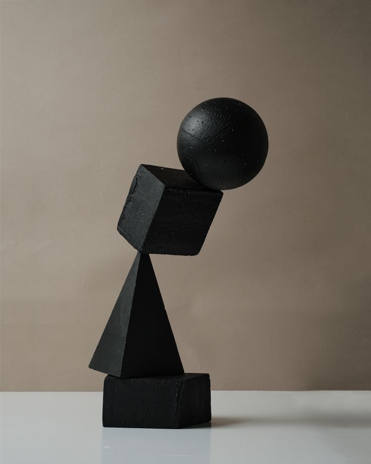 a black sculpture sitting on top of a white table next to a gray and brown wall