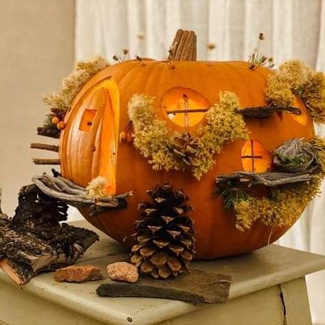 a pumpkin decorated with moss and pine cones