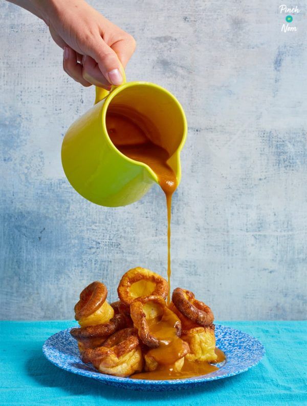 someone is pouring caramel sauce on some fried doughnuts and they are sitting on a blue plate