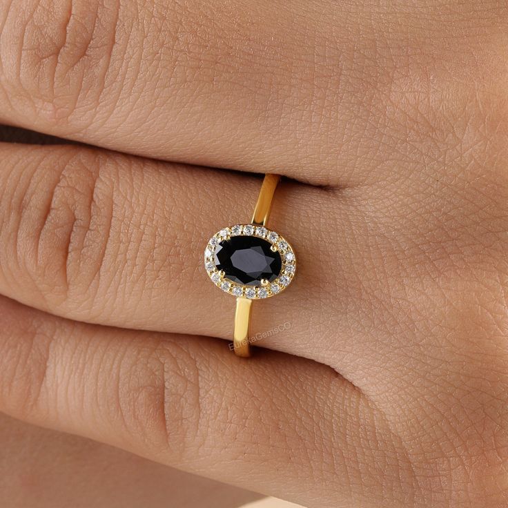 a woman's hand with a diamond and black stone ring