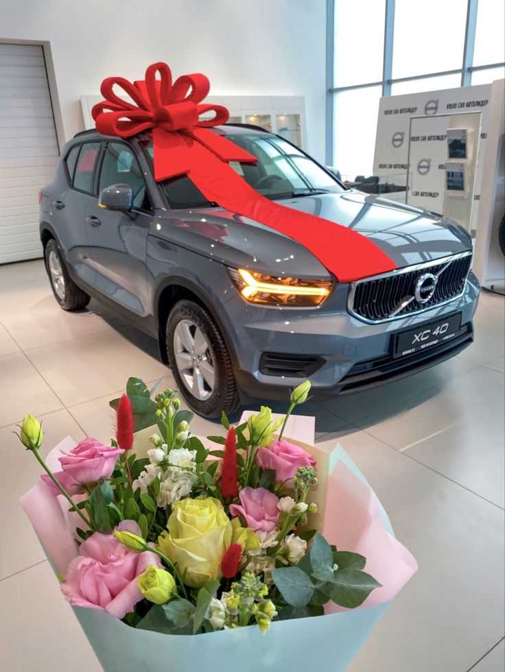 a car with a large red bow on it's hood and flowers in the front