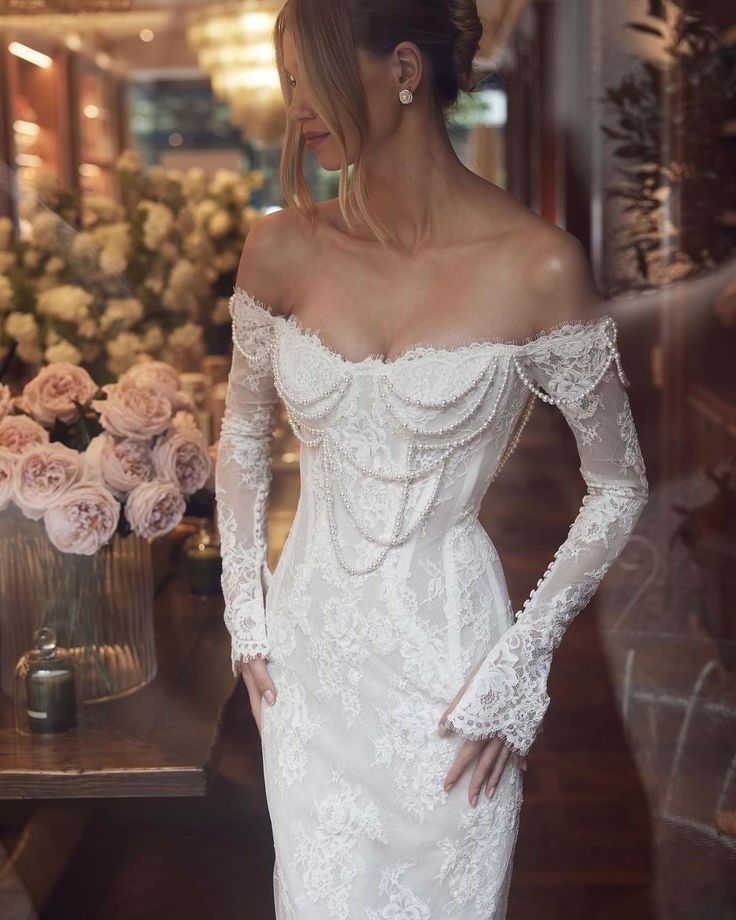 a woman in a white wedding dress standing next to flowers