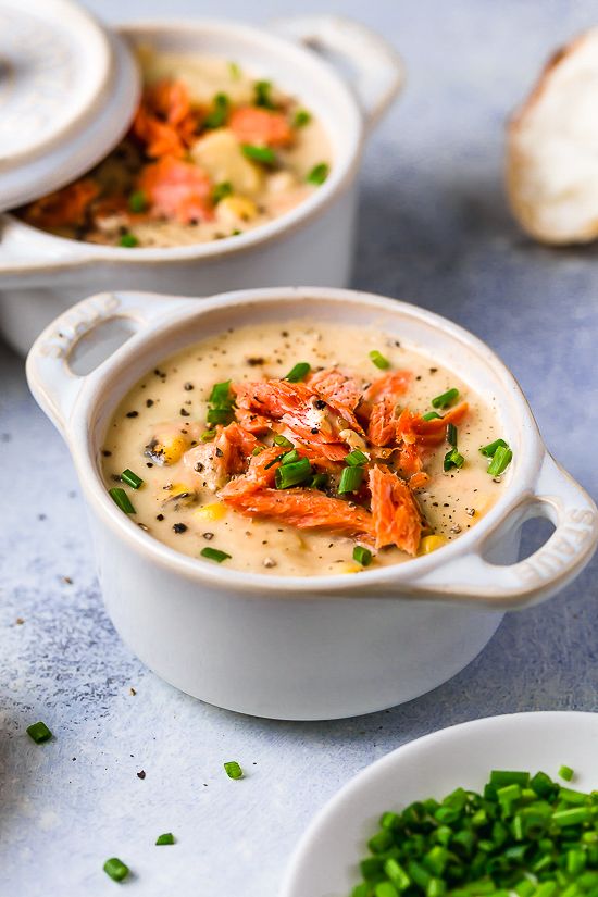 three white bowls filled with soup and garnished with green onions on the side