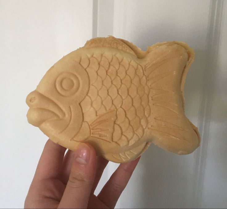 a hand holding a carved fish shaped cookie