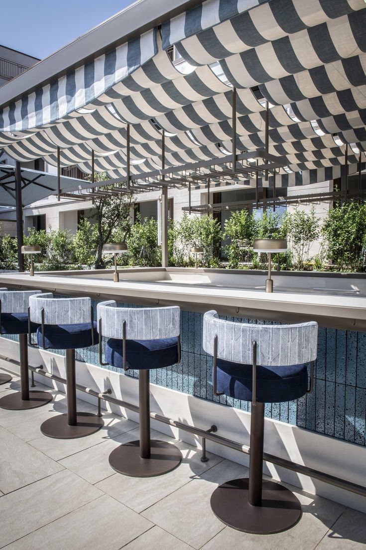 several blue and white stools sitting next to a swimming pool under an awning