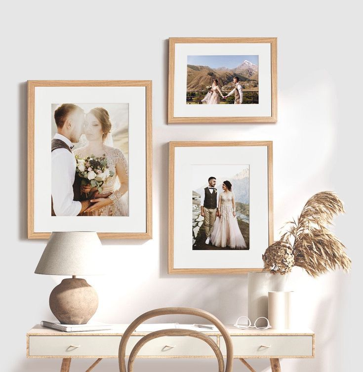 three framed photos hang on the wall above a desk with a chair and vase in front of it