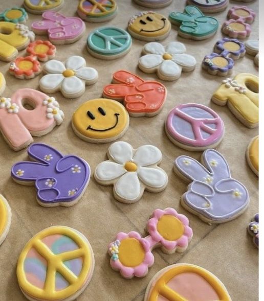 many decorated cookies are on the table with peace signs, flowers, and other decorations