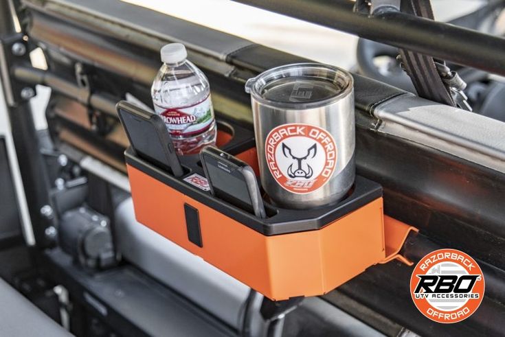 an orange and black can is sitting on the side of a vehicle with a cell phone in it