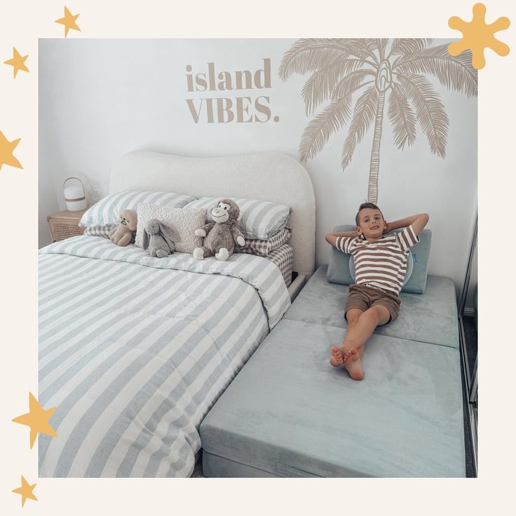 a little boy laying on top of a bed next to a palm tree