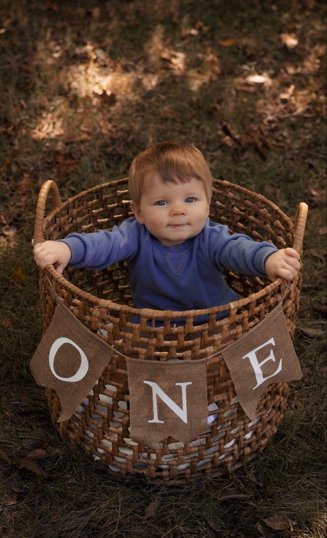 a baby sitting in a basket with the word one on it