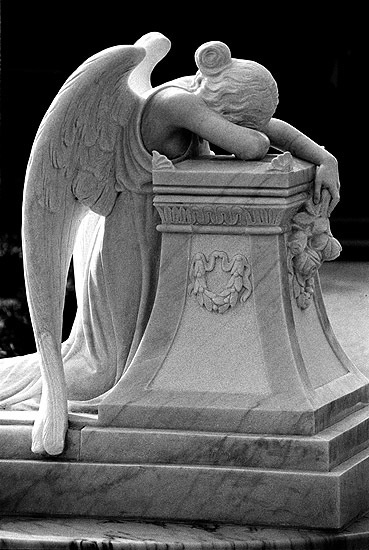 an angel statue sitting on top of a marble pedestal