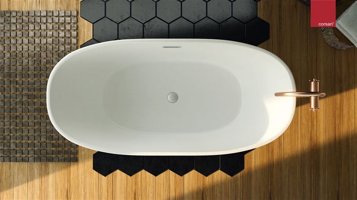 an aerial view of a bathtub and rugs in a bathroom with wood flooring