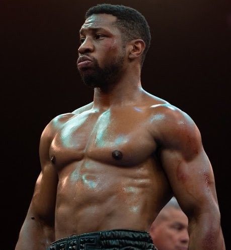 a close up of a shirtless man with his hands on his hips and looking off to the side