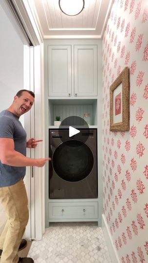 a man standing in front of a washer next to a wallpapered room