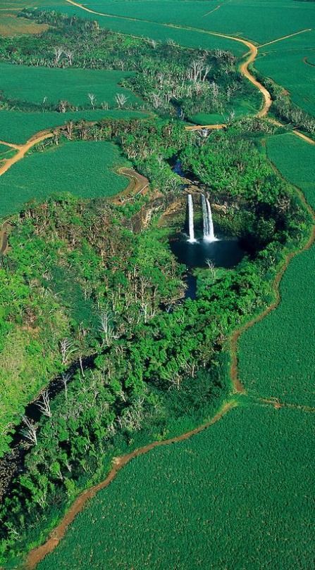 an aerial view of a waterfall surrounded by lush green fields