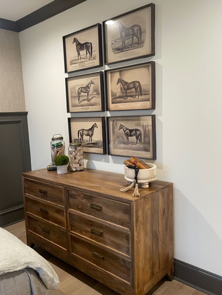 a dresser with pictures on the wall above it