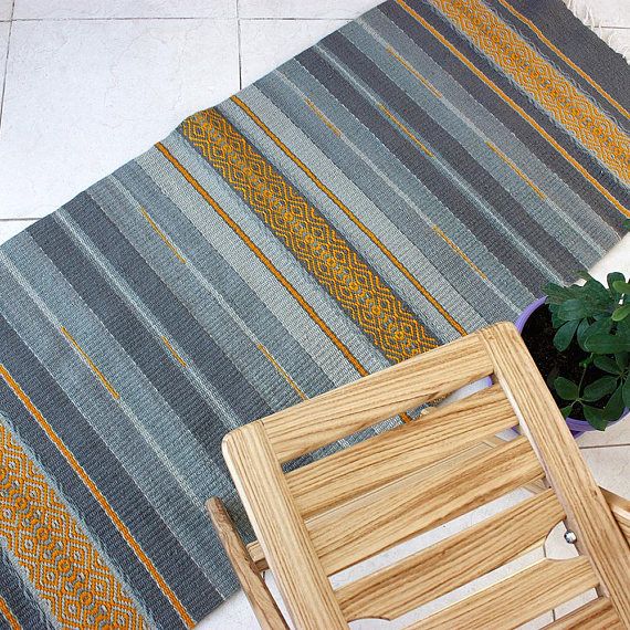 a wooden chair sitting on top of a floor next to a rug and potted plant