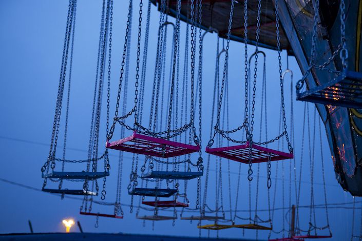 several swings suspended from the ceiling in an amusement park at night with lights on them