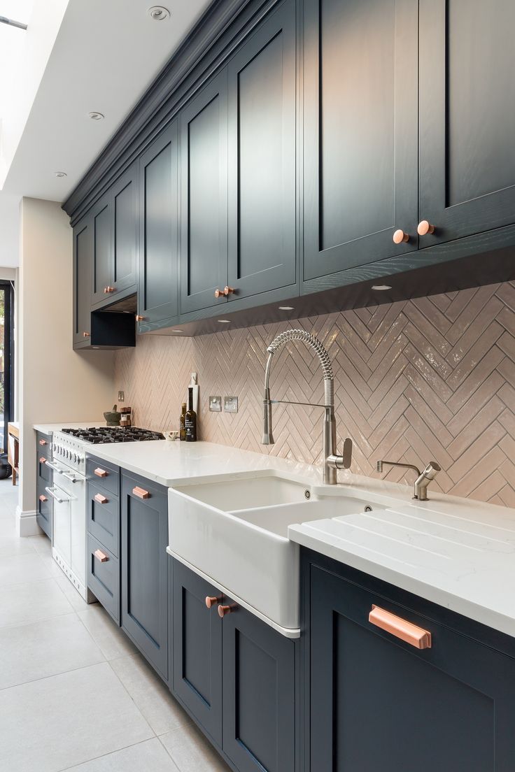 a kitchen with blue cabinets and white counter tops, along with a large sink in the center