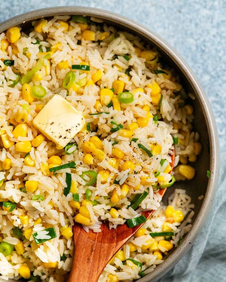 a pot filled with rice, corn and butter on top of a blue table cloth