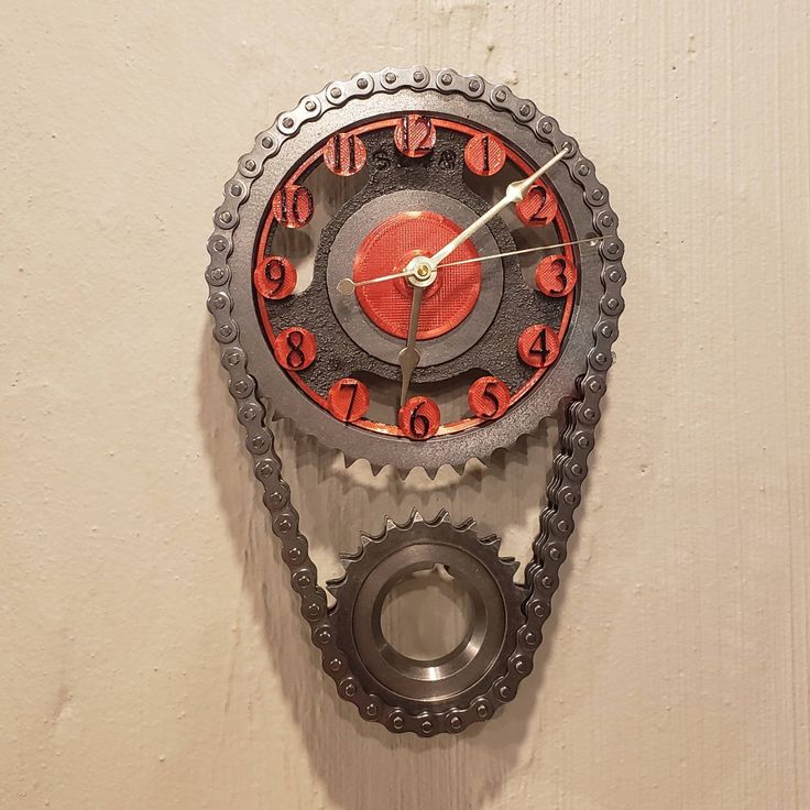 a red and black clock on the side of a wall with chains attached to it