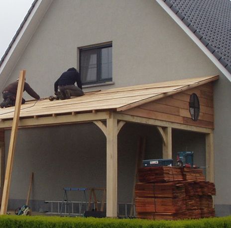 two men are working on the roof of a house that is being built with wood